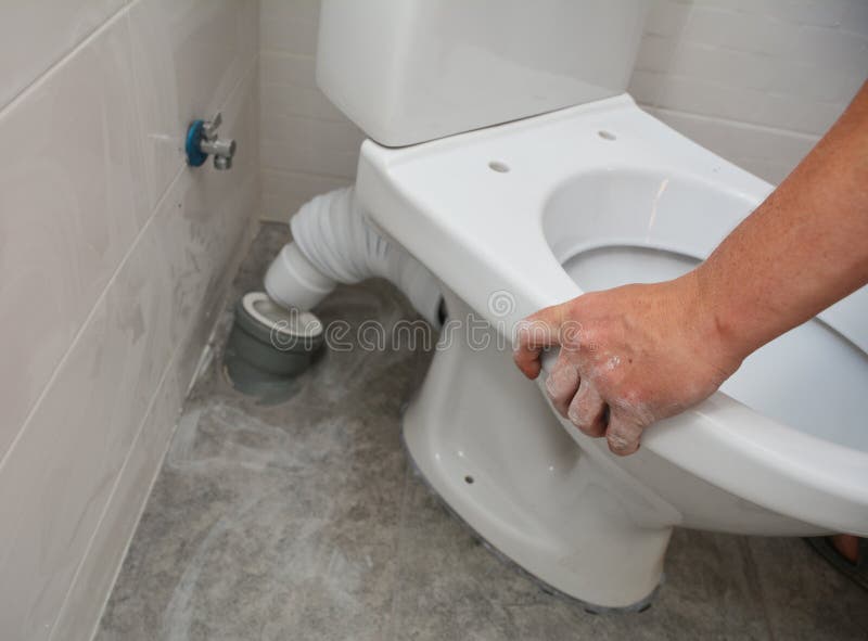 A white toilet bowl, seat installation and plumbing connecting toilet pan connector to the waste pipe and water supply pipe to the. Toilet tank in the corner of royalty free stock photography