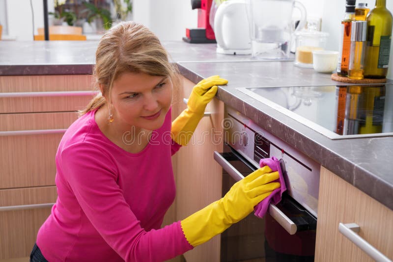 Woman cleaning the kitchen stove stock photography
