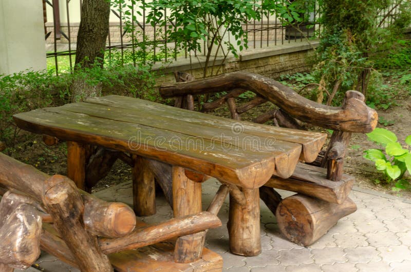 Wooden table with benches in a cafe made of rough wood and logs, home interior, design in the courtyard of a private residential b. Uilding stock photo