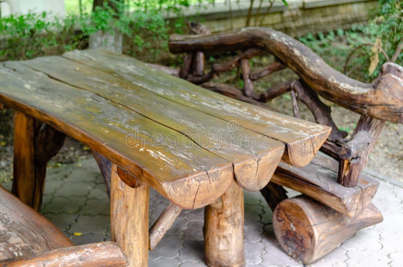 Wooden table with benches in a cafe made of rough wood and logs, home interior, design in the courtyard of a private residential b. Uilding stock photography