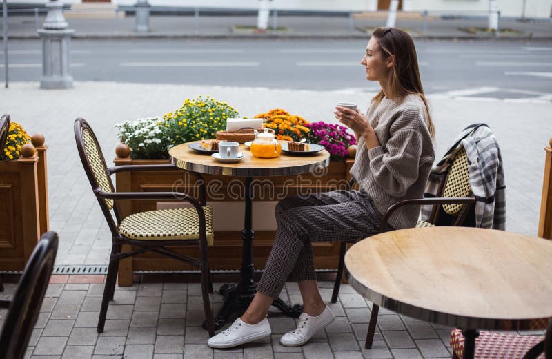 Young stylish woman having a french breakfast with coffee and cake sitting at the cafe terrace. Young stylish woman having a french breakfast with coffee and pie stock images