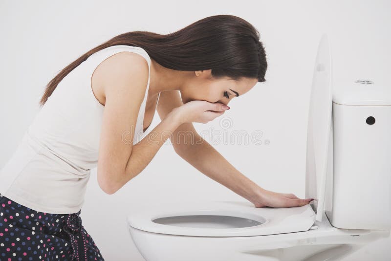 Woman in toilet. Young woman vomiting into the toilet bowl in the early stages of pregnancy or after a night of partying and drinking stock image