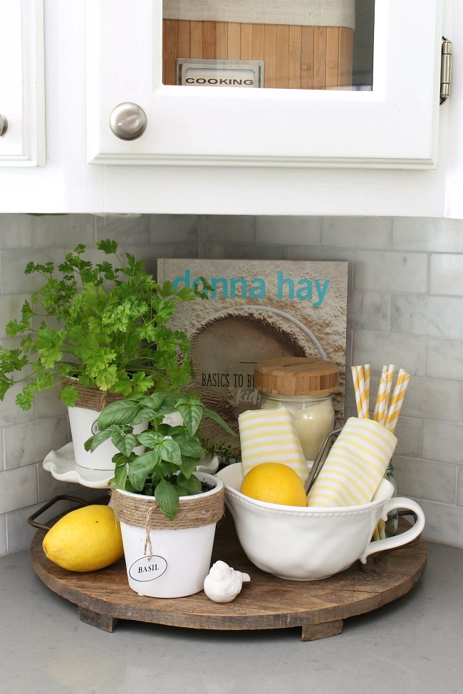 Summer vignette on a wood tray with lemons and herbs.