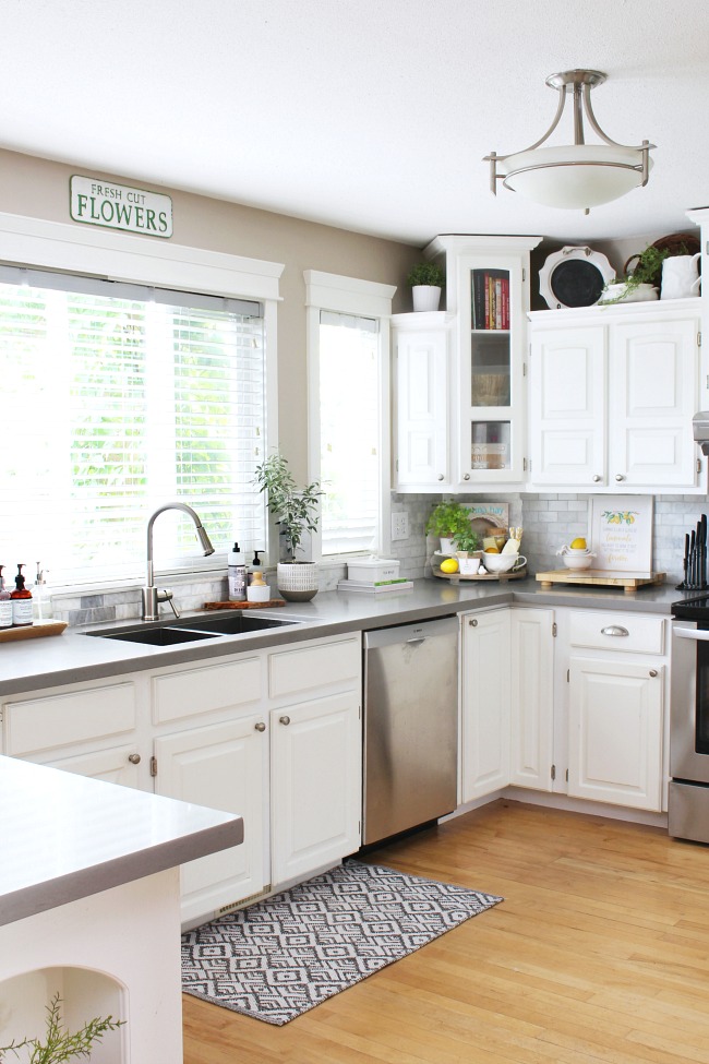 White farmhouse style kitchen decorated for summer with pops of lemon and some fresh greenery.